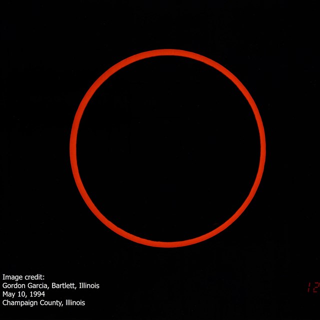 A black circle in the center of the image is surrounded by a thin glow of warm orange.