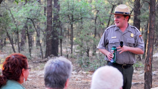 A group of park visitors listening to a ranger talk. The ranger is on the right and smiling.