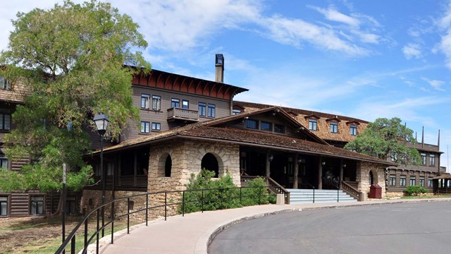 Front entrance to a four-story, chalet style, wood and stone hotel with springtime green foliage ,