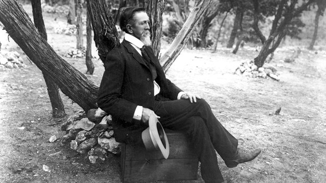 A black and white photo of a man sitting down.