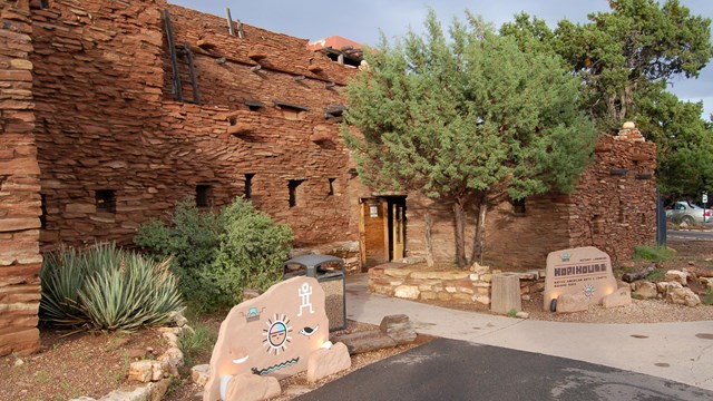 A adobe pueblo building with two signs in the front.