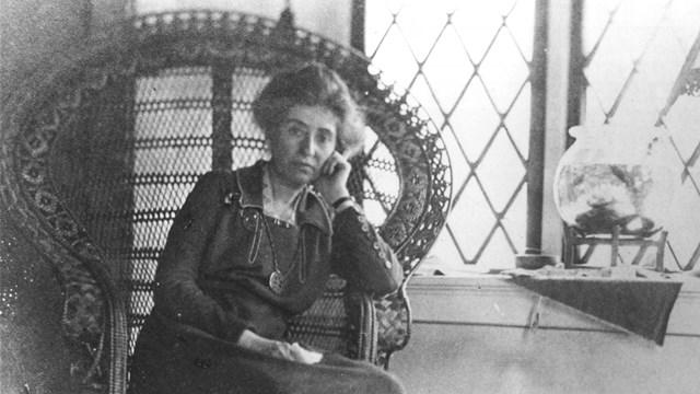 A black and white photo of a women sitting in a chair.