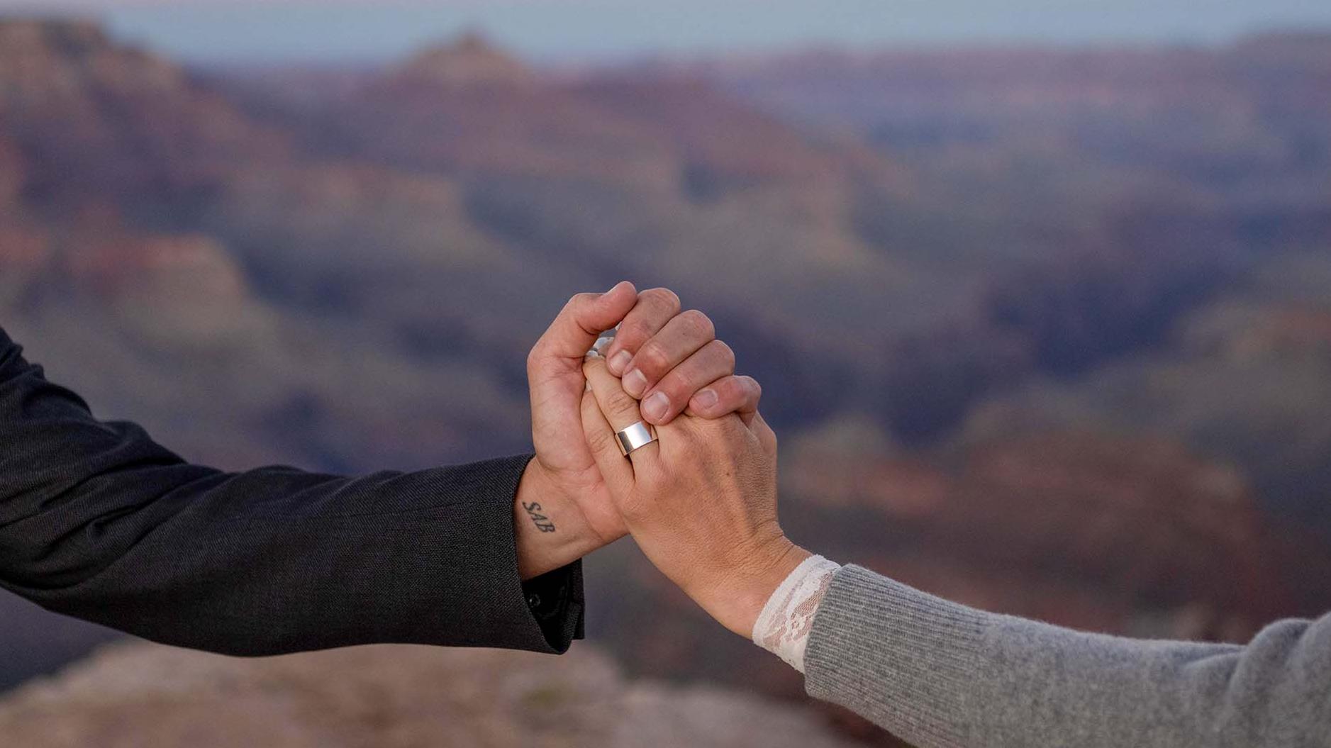 Two holding hands during a wedding ceremony with the canyon in the background.