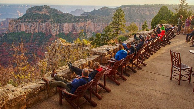 Visitors sit at the Grand Canyon Lodge veranda to watch the sunset from the North Rim.
