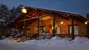 Front entrance to Bright Angel Lodge with snow on the front porch at twightlight