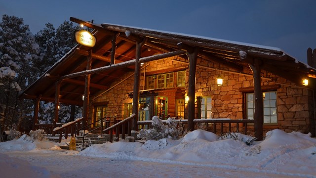 Front entrance to Bright Angel Lodge with snow on the front porch at twightlight