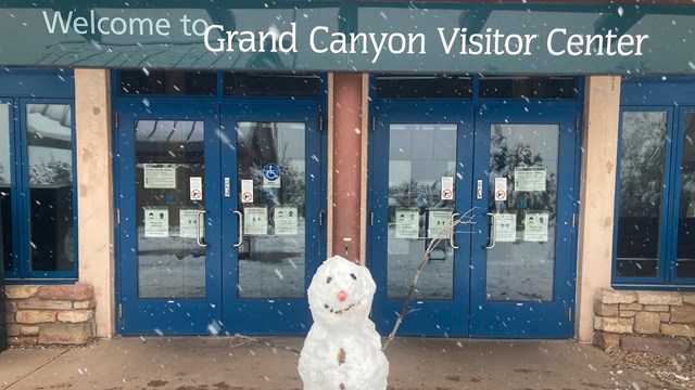 A snowman stands outside of the Grand Canyon visitor center doors