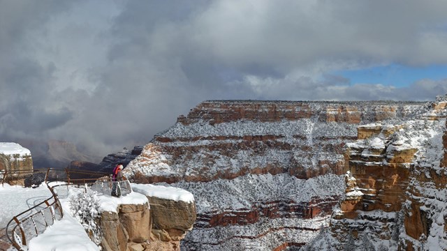 complex patterns formed by storm clouds above a vermilion colored peak within a vast landscape.