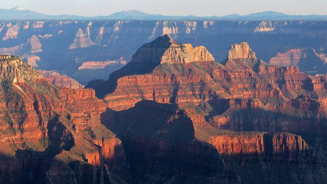 Landscape seen from Grand Canyon Lodge. Two massive reddish peaks at sunset.