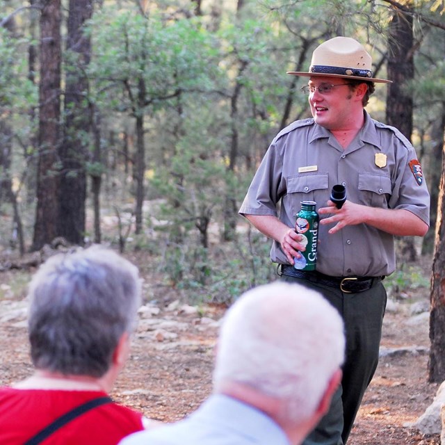 A group of park visitors listening to a ranger talk. The ranger is on the right and smiling.