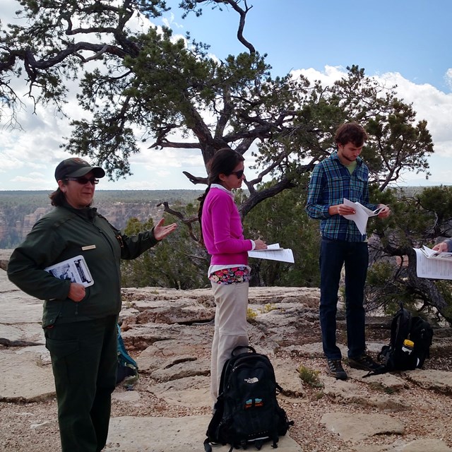 Four teachers look at reference documents while a Park Ranger leads a training session.