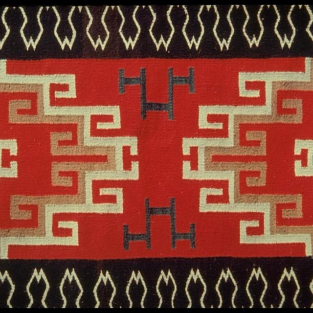 A red, white, and black symmetrical and geometric Navajo weaving.