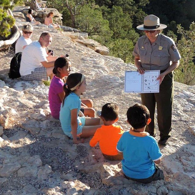 A ranger helps a group of four kids with there Junior Ranger book.