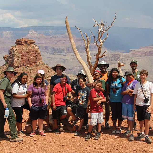 A group of kids, a couple teachers, and a couple of park rangers with the canyon in the background.