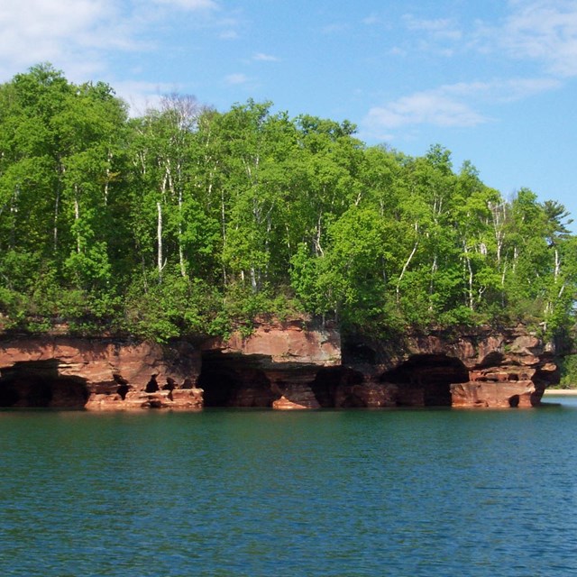 Tree-topped rock arches rising above waters of Lake Superior