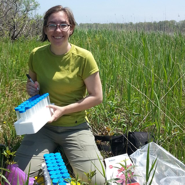  A scientist sits in a wetland with her reserach equipment.