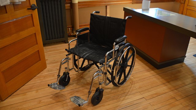 An empty wheelchair in a room with wood floors.