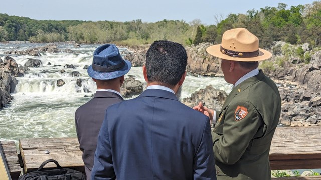 Ranger in formal uniform overlooking the falls with two men in suits. 