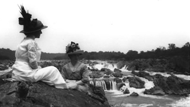 Two women sit on a cliff and enjoy viewing the Great Falls of VA
