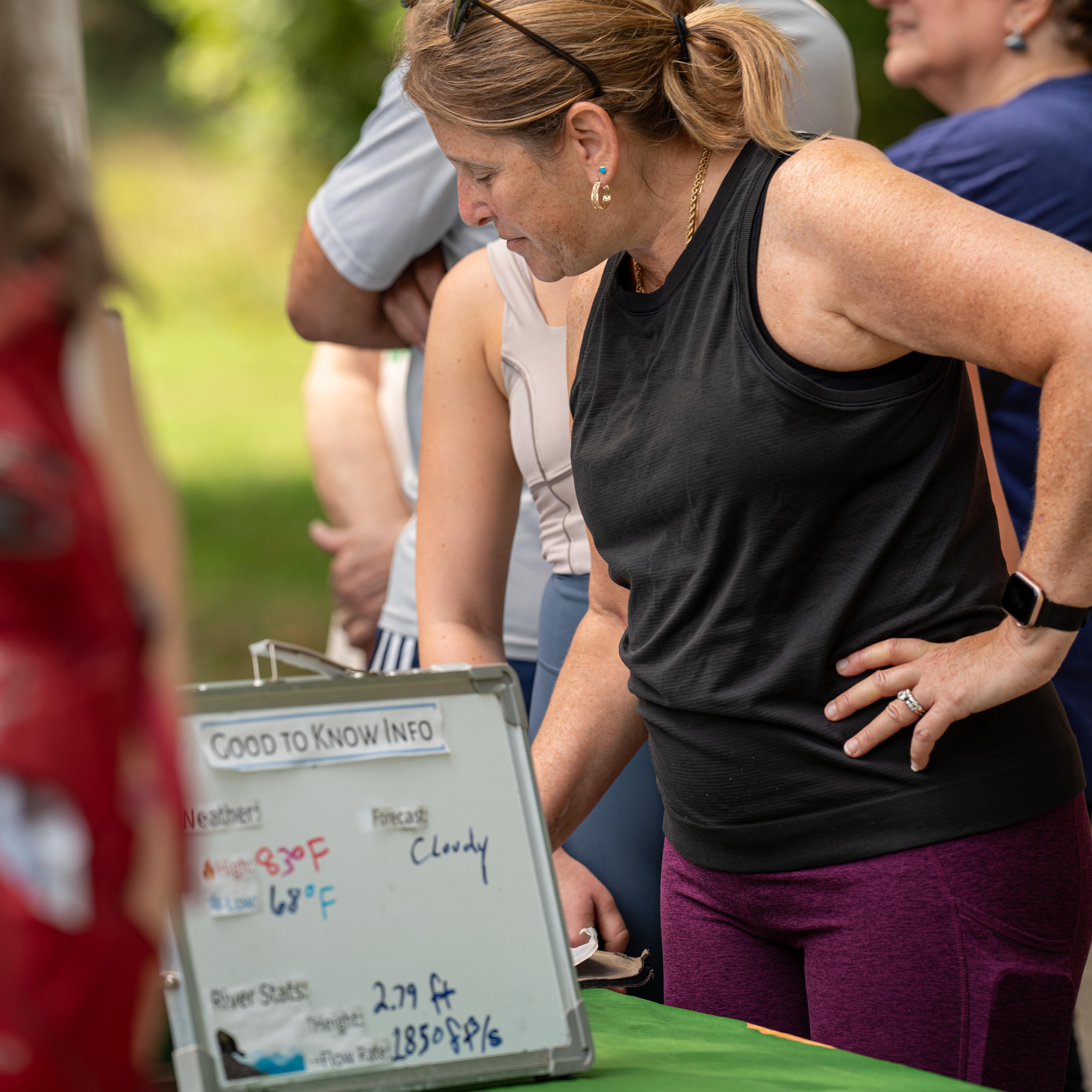 Female visitor looks at a information behind a sign that gives information about the forecast.