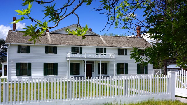 Historic ranch house; white clapboard siding with green shutters, two story design.