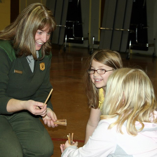 Female ranger kneels on left and two girls kneel on right