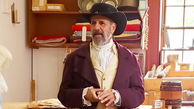 A person wearing historic clothing, talking with an audience.