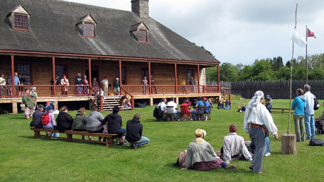 Many people on a lawn in front of a historic building.