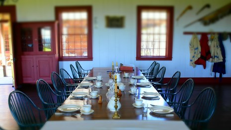 Long table set for a meal with table cloth, dishes, lanterns