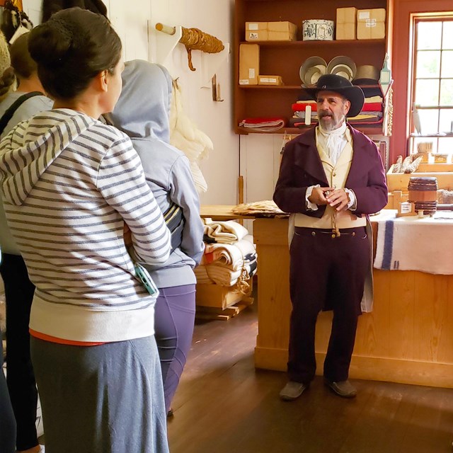 A person in historic clothing speaks to a group of people.