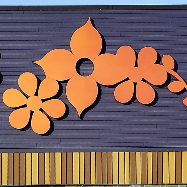 Ojibwe stylized yellow, orange, and red flower decoration on the side of a building.