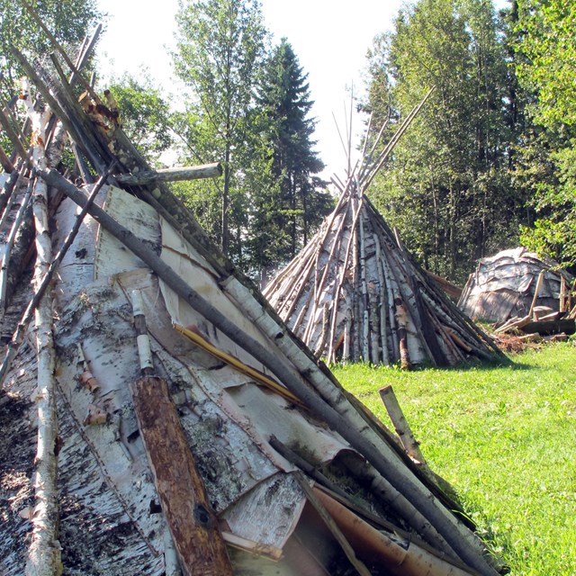 Three birch bark lodges in different shapes.