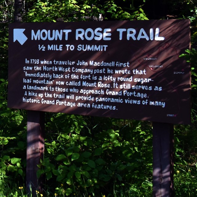 A sign in the forest at the start of a trail.