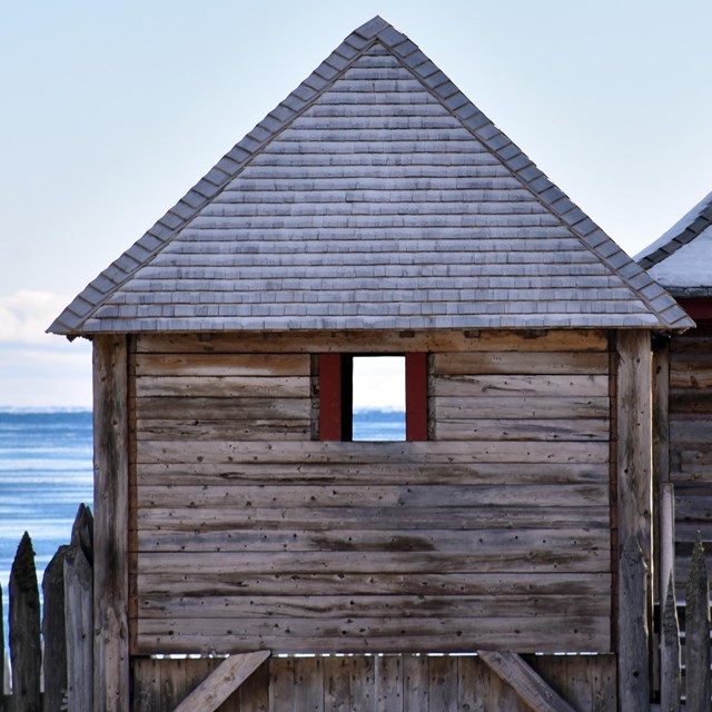 Historic wooden building with a lake in the background.