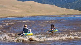 Two children floating Medano Creek