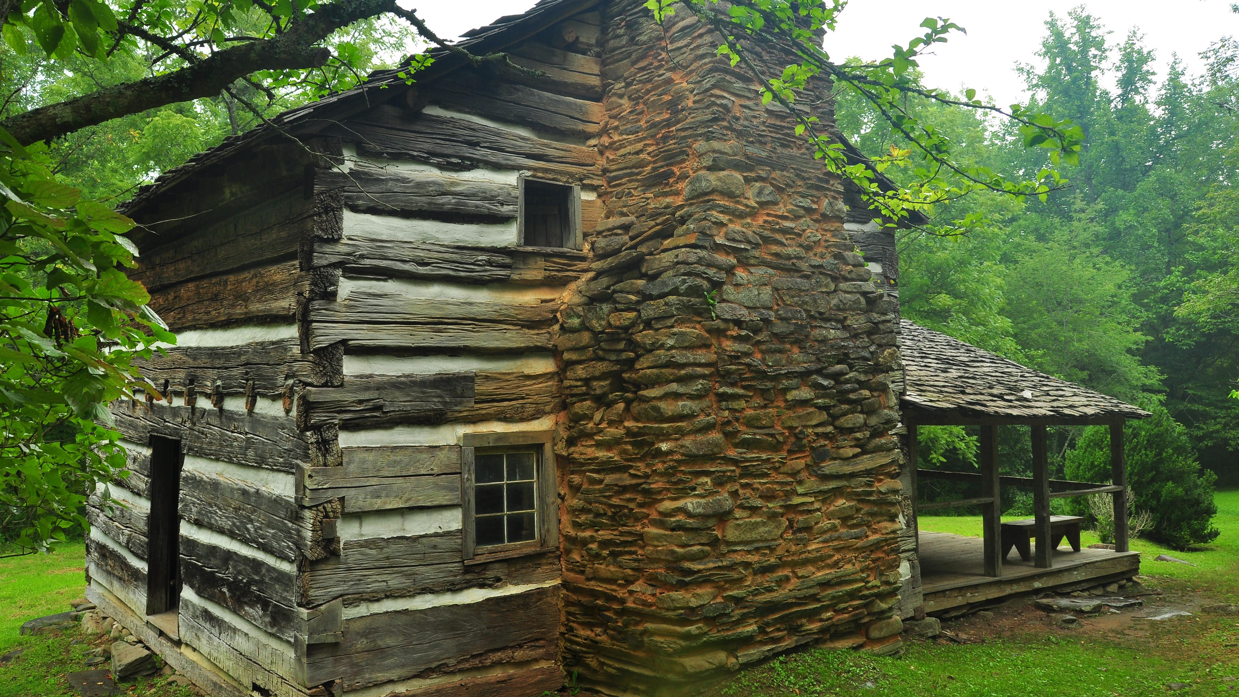 A log cabin with a stone chimney.