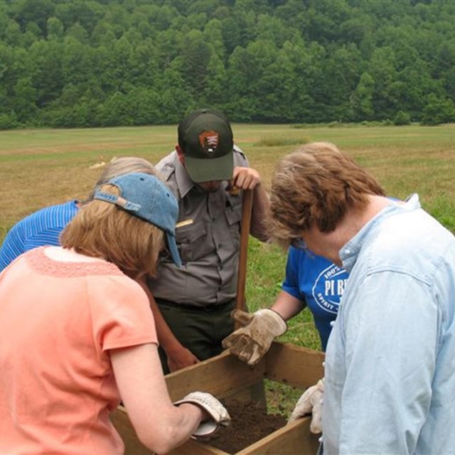 Four teachers and a ranger looking at equipment.