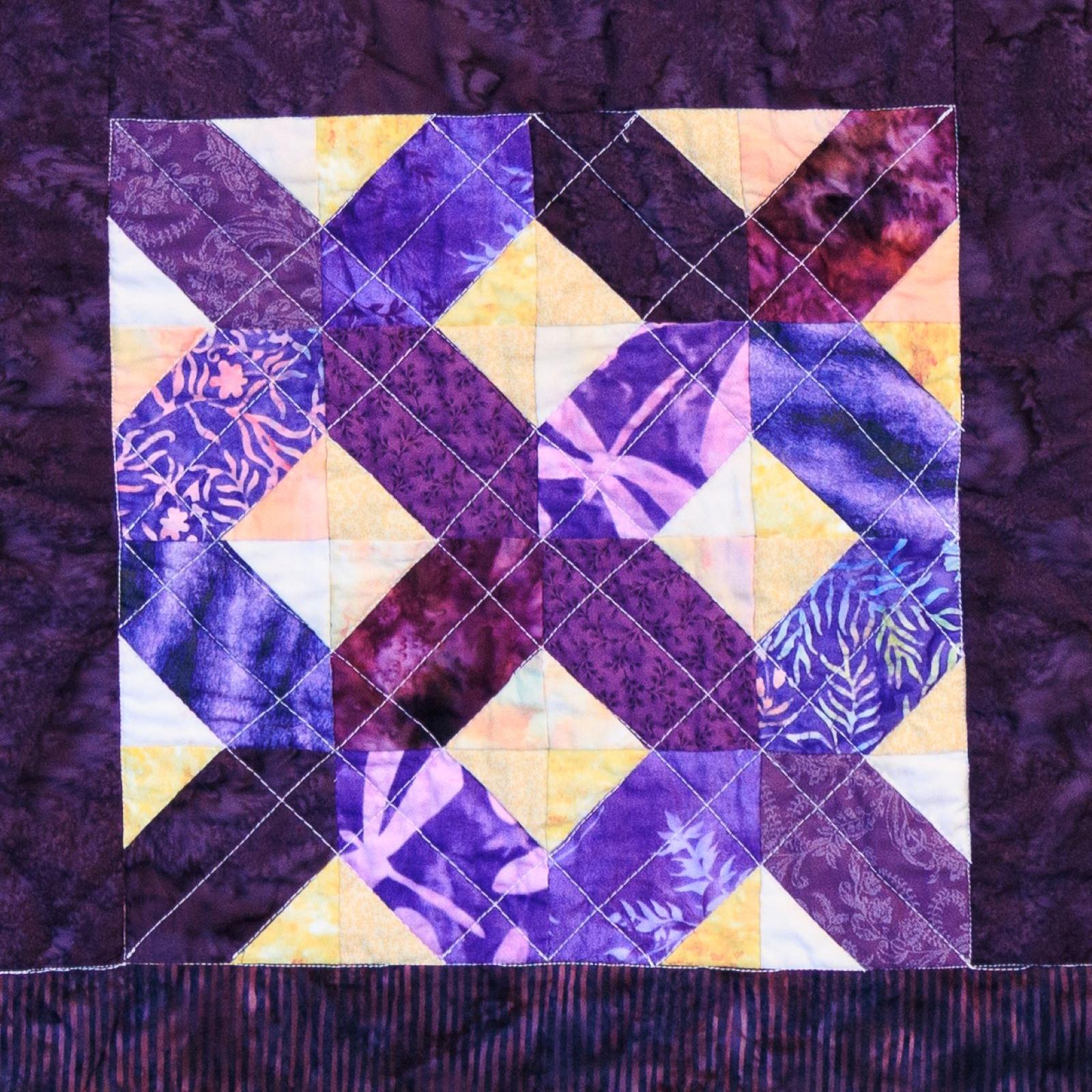 A quilt block that is yellow and purple.