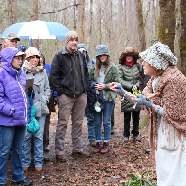 Volunteer in costume talking to visitors outside.