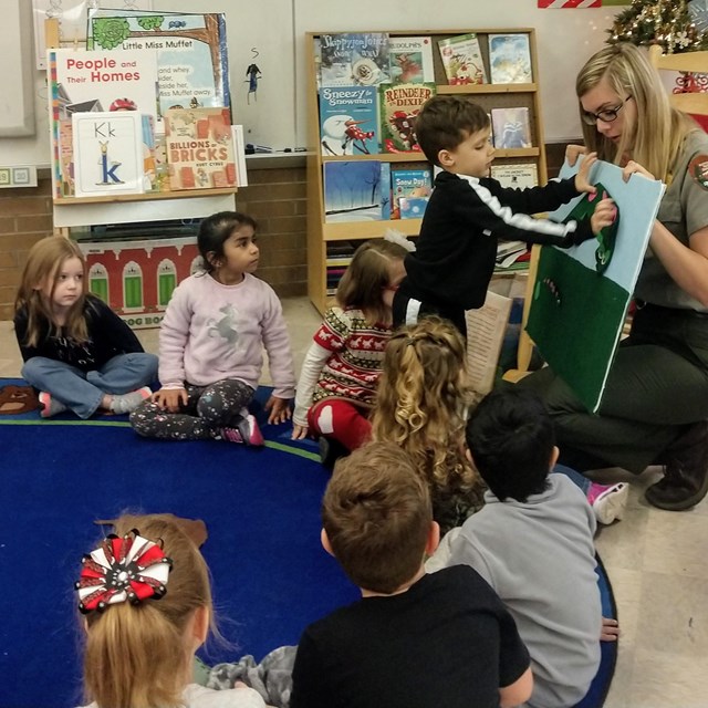 Students looking at board held by a Ranger in a classroom.