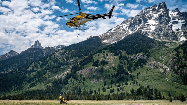 A helicopter performs an operation in front of a mountain.