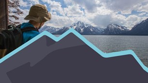 Hiker looking across a lake at the Teton Range.