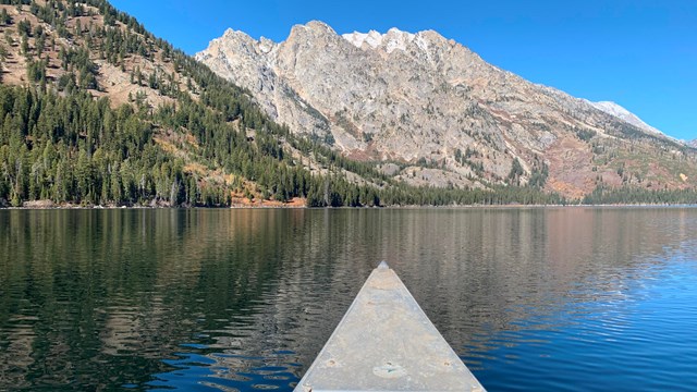 The front of a canoe on a lake.