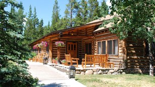 A log building with chairs on the porch.