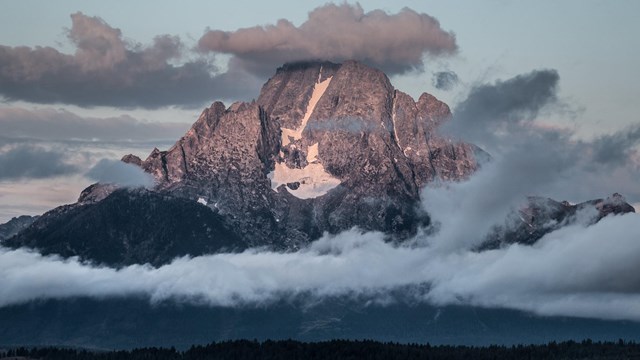 Mount Moran at sunrise with clouds. Skillet Glacier and the Black Dike are prominent.