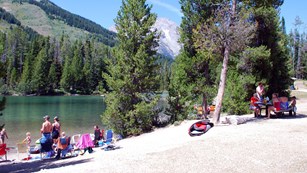 Looking north along the Teton Range as visitors picnicking on the shores of String Lake.