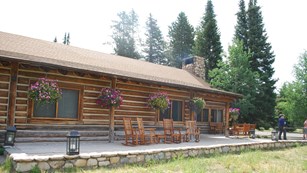 A log cabin with chairs on the porch.