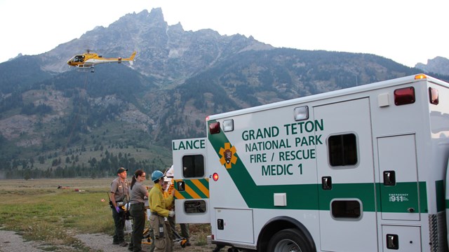 Ambulance and helicopter in front of Mount Teewinot.