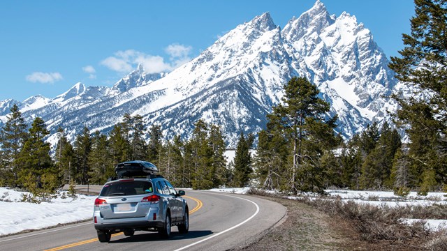 A car drives on a road towards mountains.