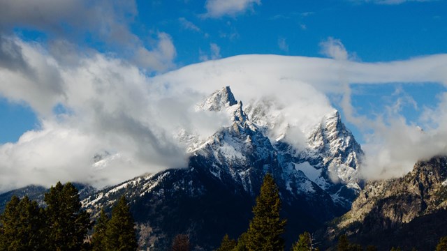 Clouds rise off of mountains.